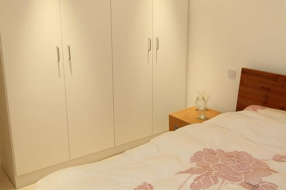 View bedroom interiors with a wooden headboard matching a bespoke bedside table made from recycled Milo wood