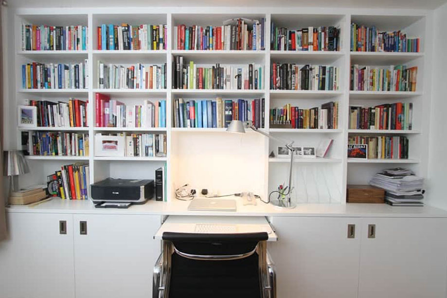 Full view of White painted bookcase with bottom cabinets with doors and a oull out cumputer desk