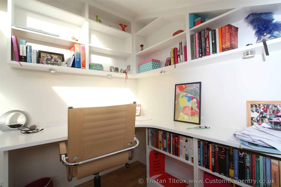 Bottom angle view of fitted home office bookshelves with spot down LED lights on the desk