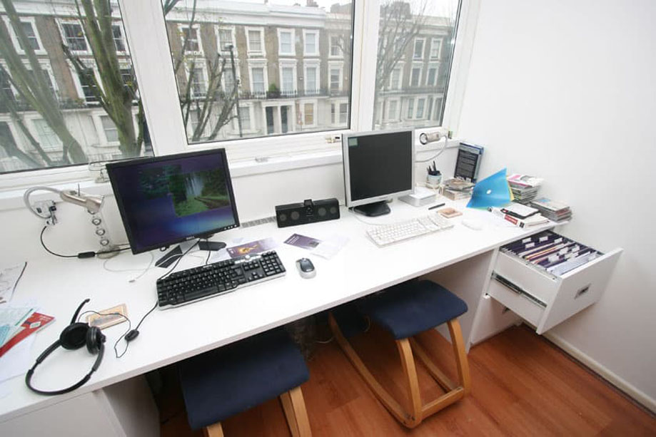 Modern home office desk facing big enough for two desktop computers facing a window