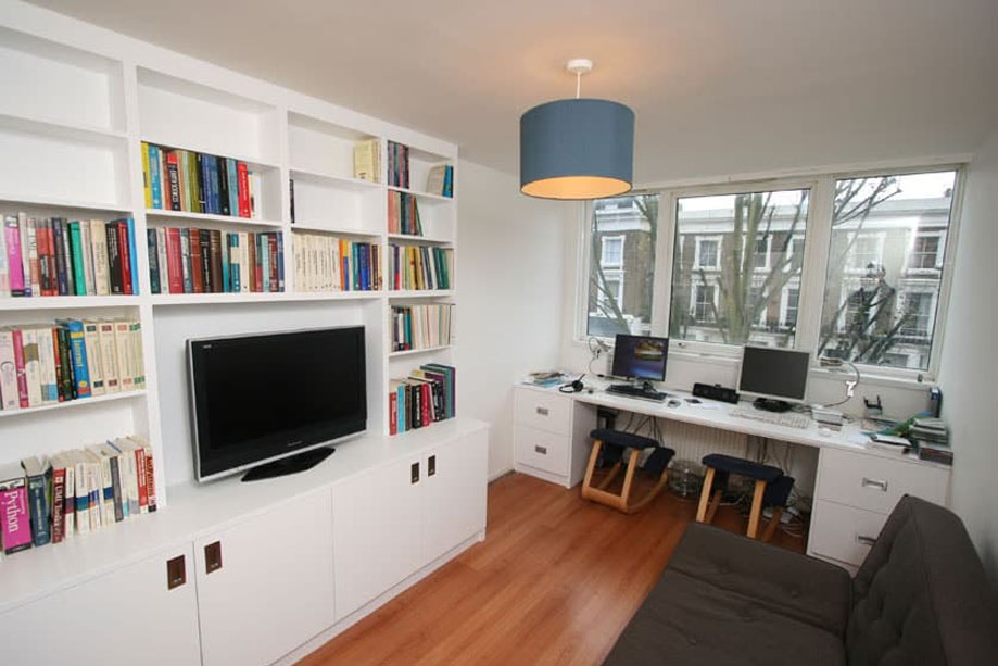 View of living area with large built in media unit with bookcase and a home office desk by the window