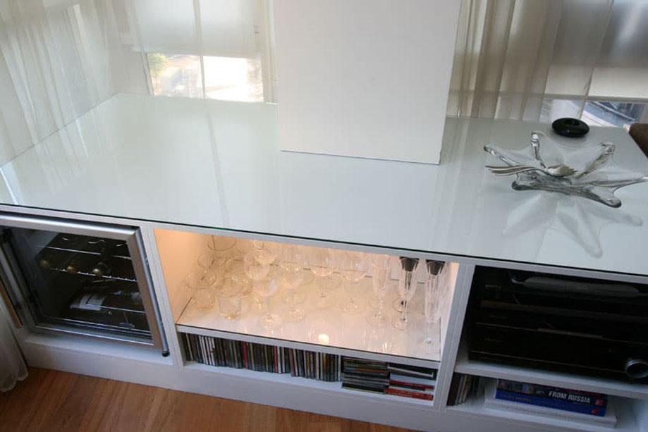 Closer view of low media unit with glass table top 5 storage shelves and LED light on the middle shelf