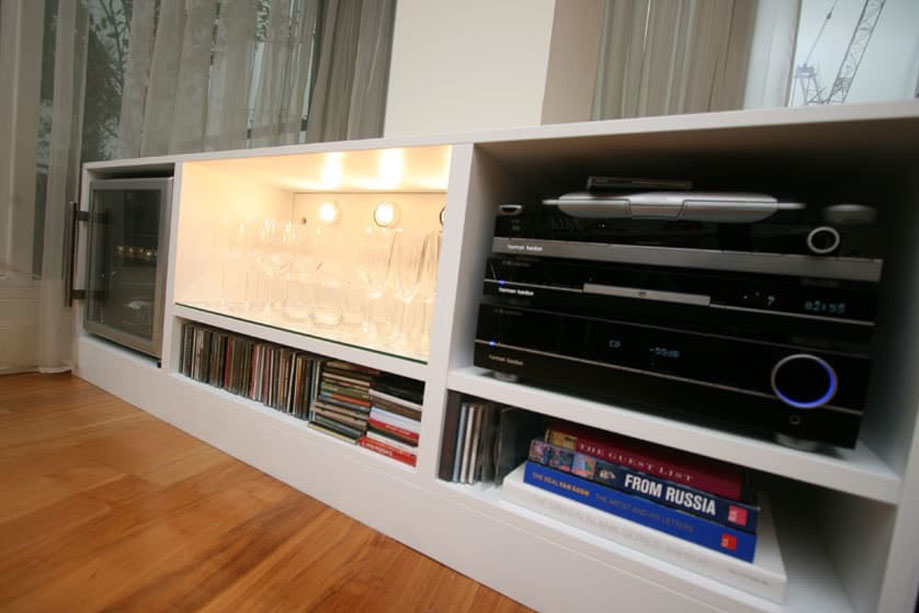 Low White painted media unit with glassdoor wine cabinet, console shelves and LED backlights on the middle shelf