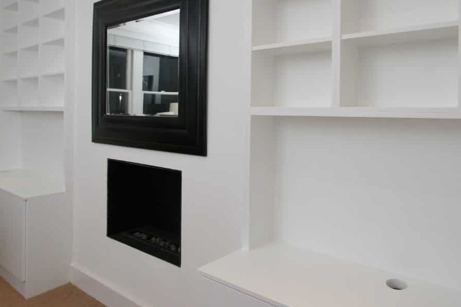 2 White painted media cabinets with library bookcase, tabletop for TV storage, and wall mounted mirror and fireplace in between