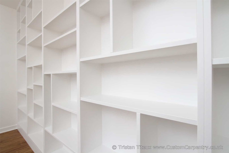 Right side view of floor to ceiling library bookcase with asymmetrical shelves all handpainted White