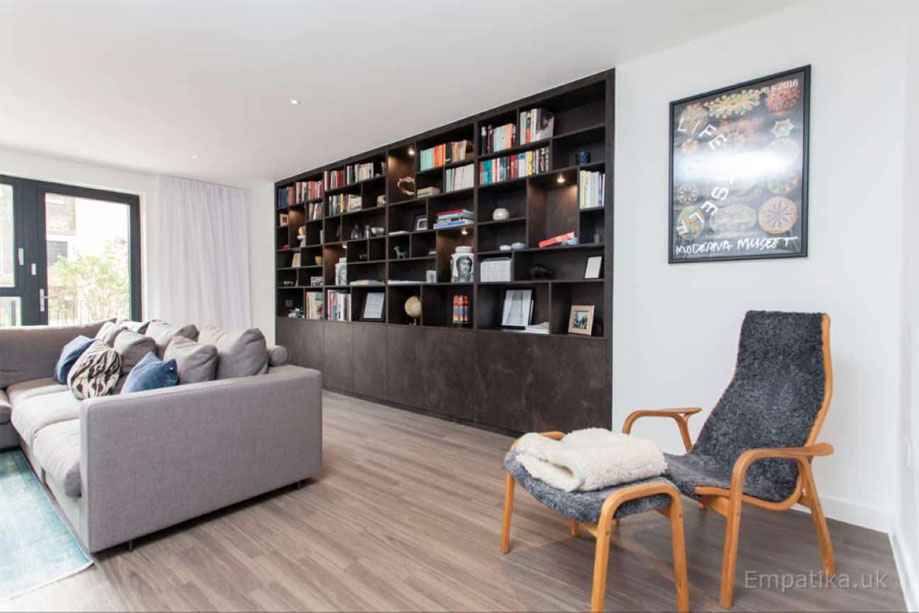 View of spacious living room with large built in dark coloured display unit with bookcase and bottom closets